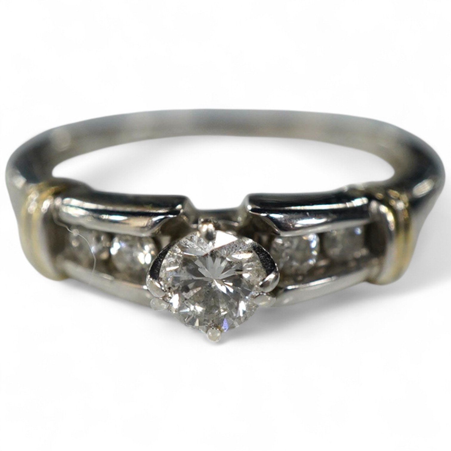 A diamond ring, claw-set with a brilliant-cut diamond weighing approximately 0.30 carats, to shoulders channel-set with smaller brilliant-cut diamonds, mounted in white gold, size R, stamped 14K, gross weight approximate